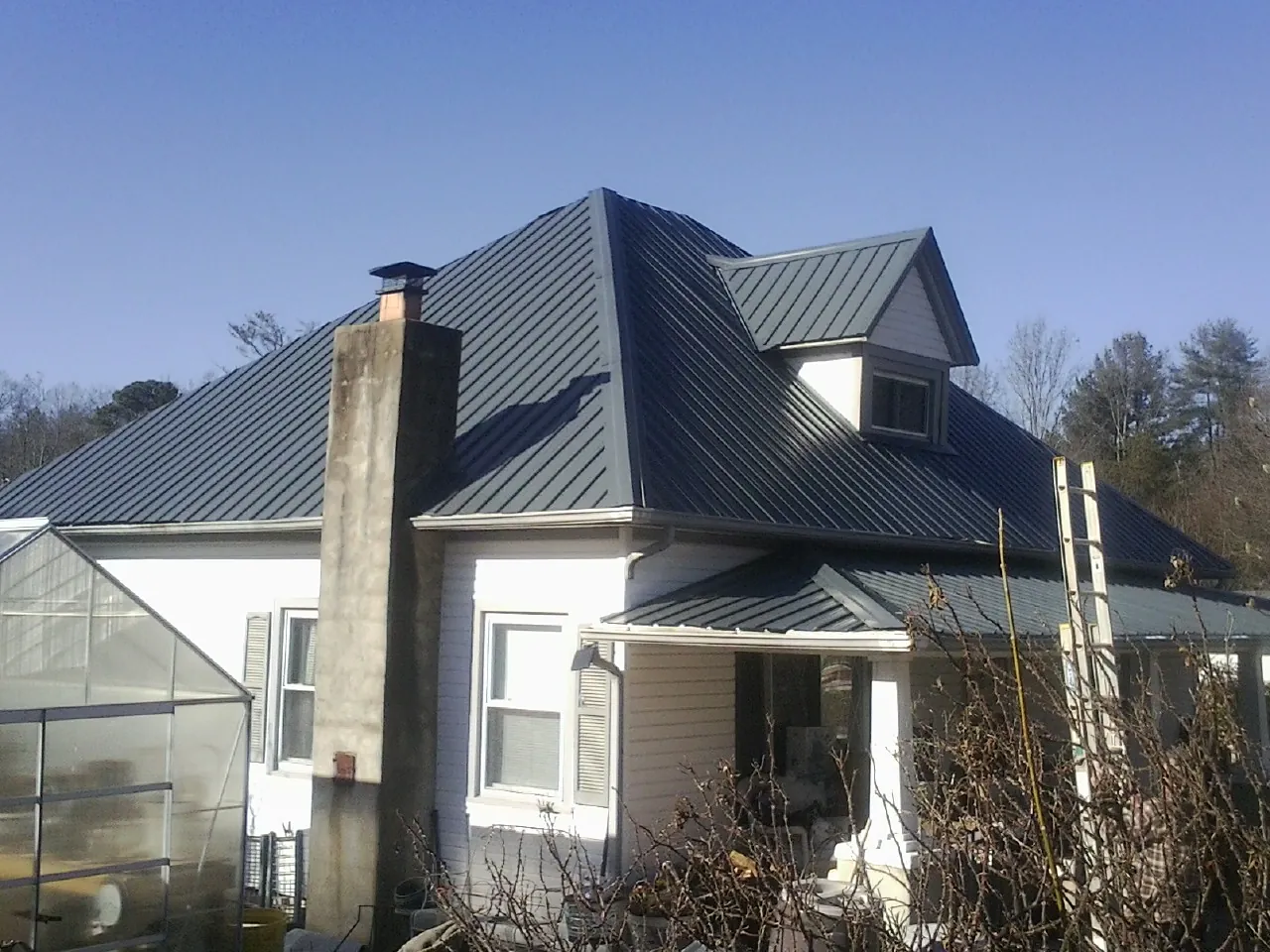 Dark blue standing seam metal roof on a white farmhouse with dormer — Slate & Tile Roof Repair by Roofing Brothers in Chandlersville