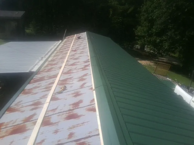 Old rusted panels beside newly installed green metal roofing — Wind Damage Roof Repair by Roofing Brothers in Chandlersville