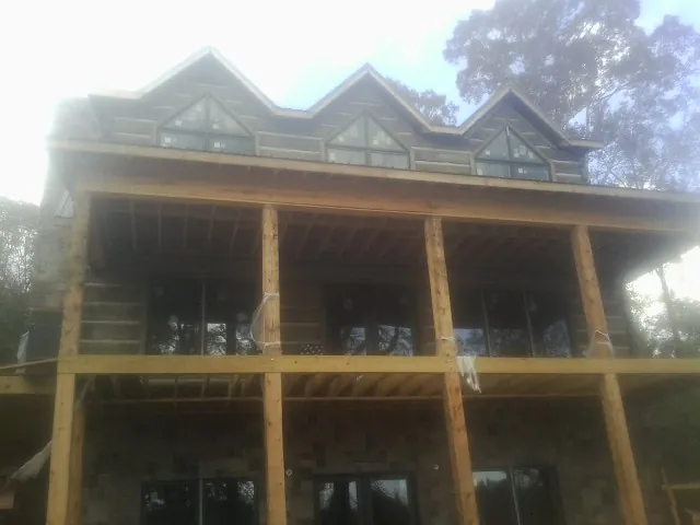 Dormers and porch framing on a large log home under construction — Roof Coating work by our crew in Chandlersville