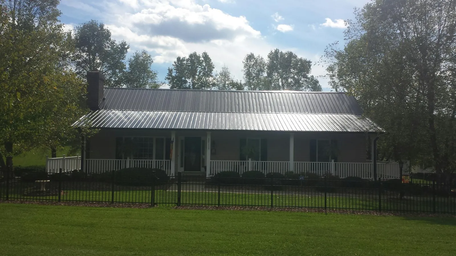 Gray metal roof on a brick ranch with a full width front porch — Gutter Guard Installation work by our crew in Chandlersville