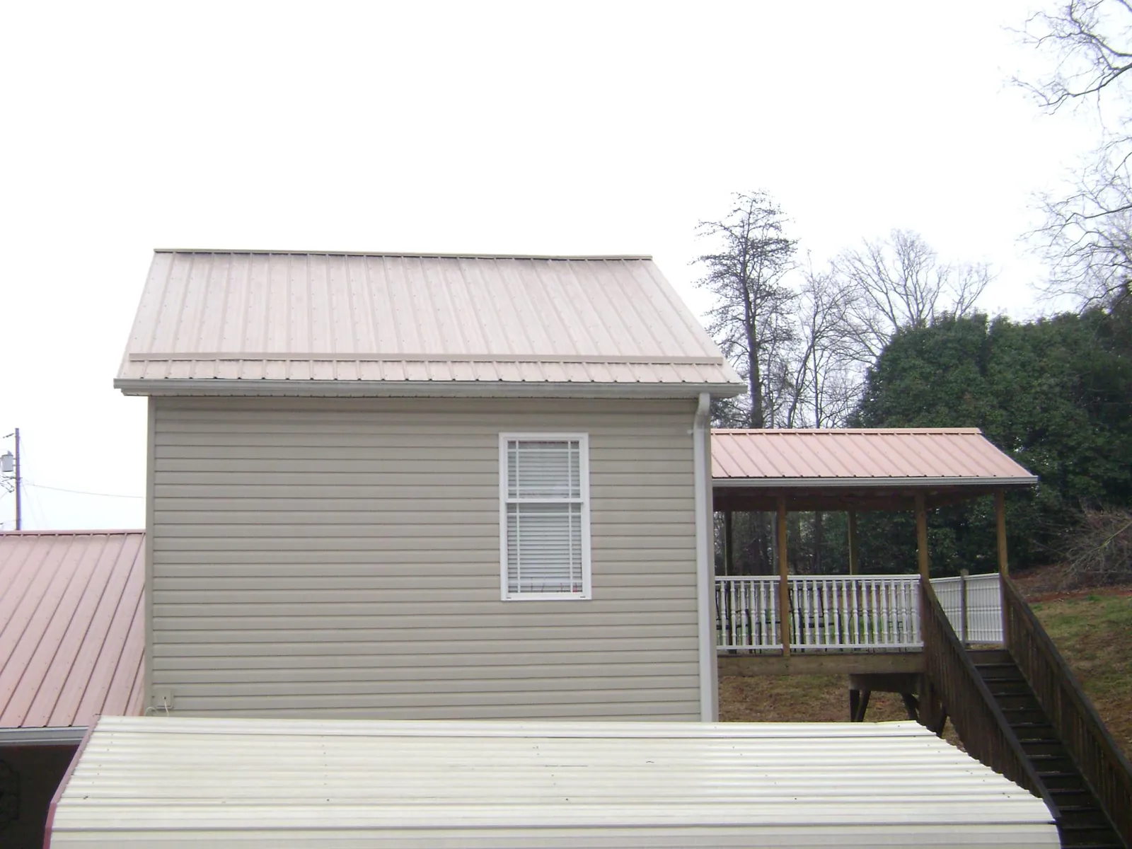 Tan metal roofs on a two story addition and attached porch, from a Roof Replacement job in Chandlersville