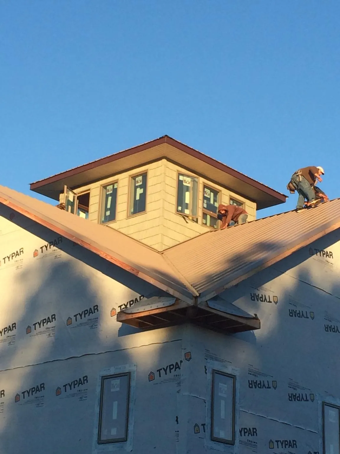 Roofers working around a rooftop cupola on a new metal roof at sunset — Roof Waterproofing in Chandlersville by Roofing Brothers